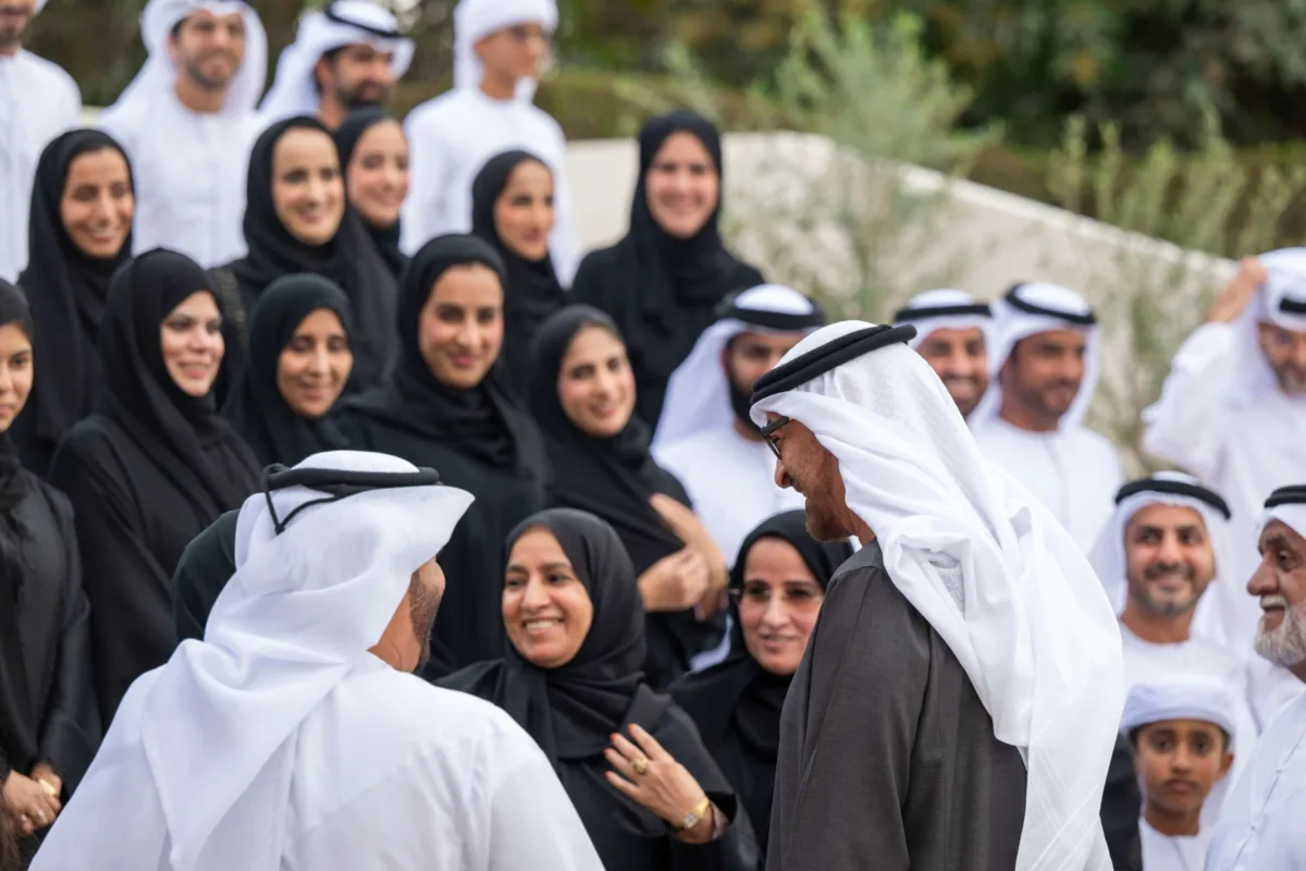 صاحب السمو الشيخ محمد بن زايد آل نهيان، رئيس دولة الإمارات، يلتقي أفراد عائلة الصيري القمزي خلال مناسبة رسمية في الهواء الطلق، محاطًا بعدد كبير من الرجال والنساء والأطفال بملابسهم الوطنية، تكريمًا لدور العائلة في الإشراف على مزرعة الشيخ زايد في الخوانيج.
