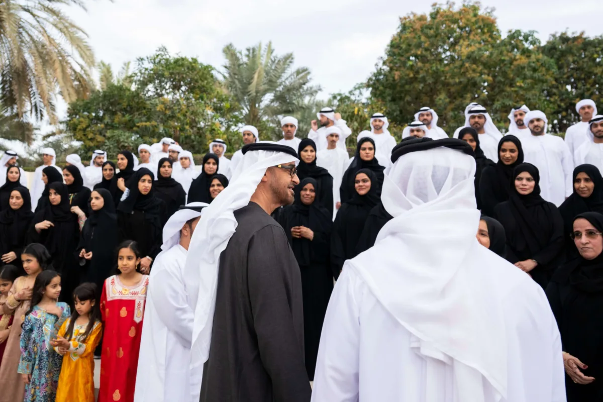 صاحب السمو الشيخ محمد بن زايد آل نهيان، رئيس دولة الإمارات، يلتقي أفراد عائلة الصيري القمزي خلال مناسبة رسمية في الهواء الطلق، محاطًا بعدد كبير من الرجال والنساء والأطفال بملابسهم الوطنية، تكريمًا لدور العائلة في الإشراف على مزرعة الشيخ زايد في الخوانيج.