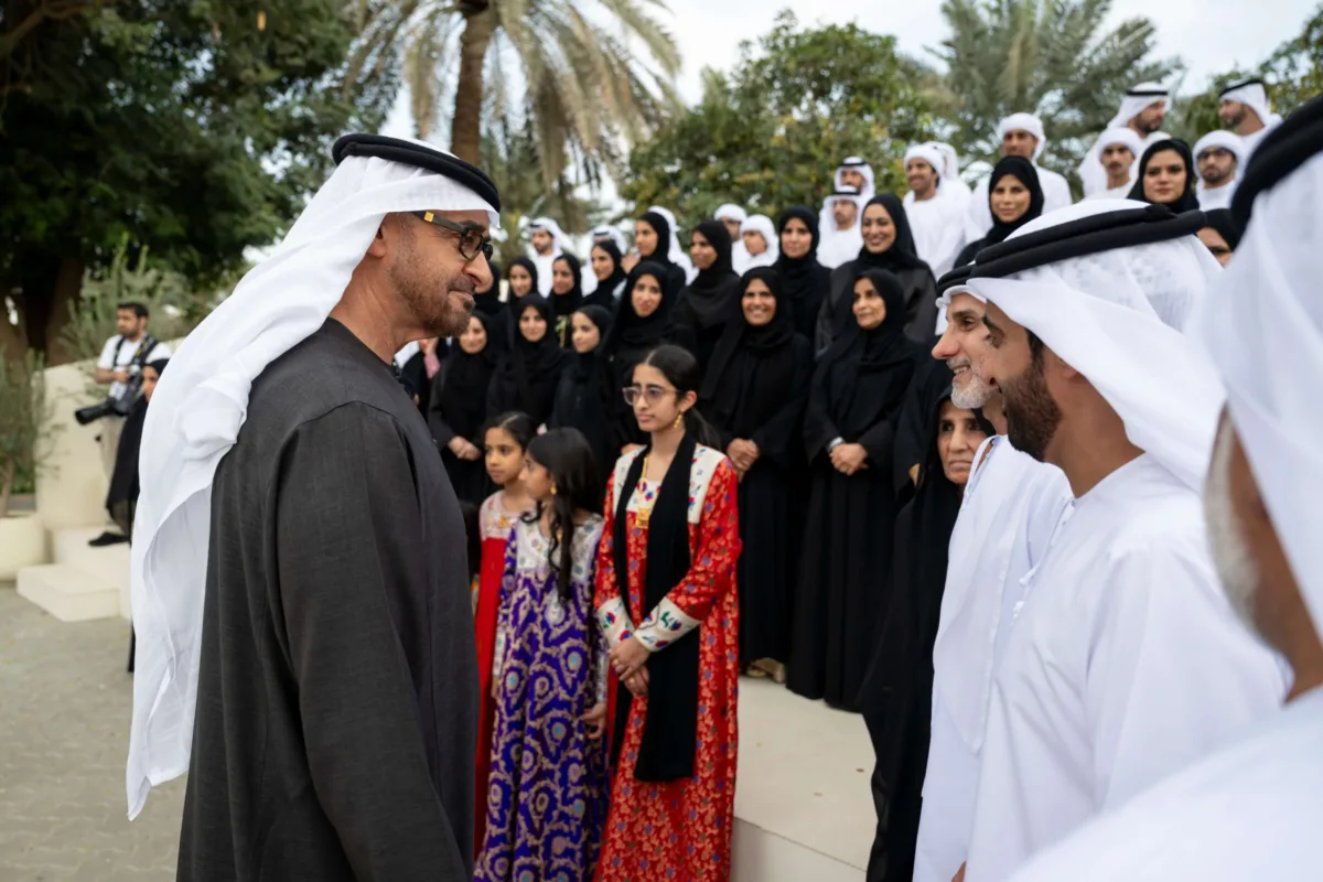 صاحب السمو الشيخ محمد بن زايد آل نهيان، رئيس دولة الإمارات، يلتقي أفراد عائلة الصيري القمزي خلال مناسبة رسمية في الهواء الطلق، محاطًا بعدد كبير من الرجال والنساء والأطفال بملابسهم الوطنية، تكريمًا لدور العائلة في الإشراف على مزرعة الشيخ زايد في الخوانيج.
