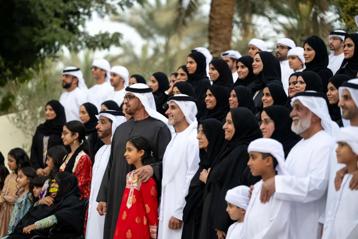 صاحب السمو الشيخ محمد بن زايد آل نهيان، رئيس دولة الإمارات، يلتقي أفراد عائلة الصيري القمزي خلال مناسبة رسمية في الهواء الطلق، محاطًا بعدد كبير من الرجال والنساء والأطفال بملابسهم الوطنية، تكريمًا لدور العائلة في الإشراف على مزرعة الشيخ زايد في الخوانيج.